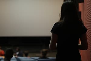 Devojka stoji okrenuta leđima ispred bioskopskog platna